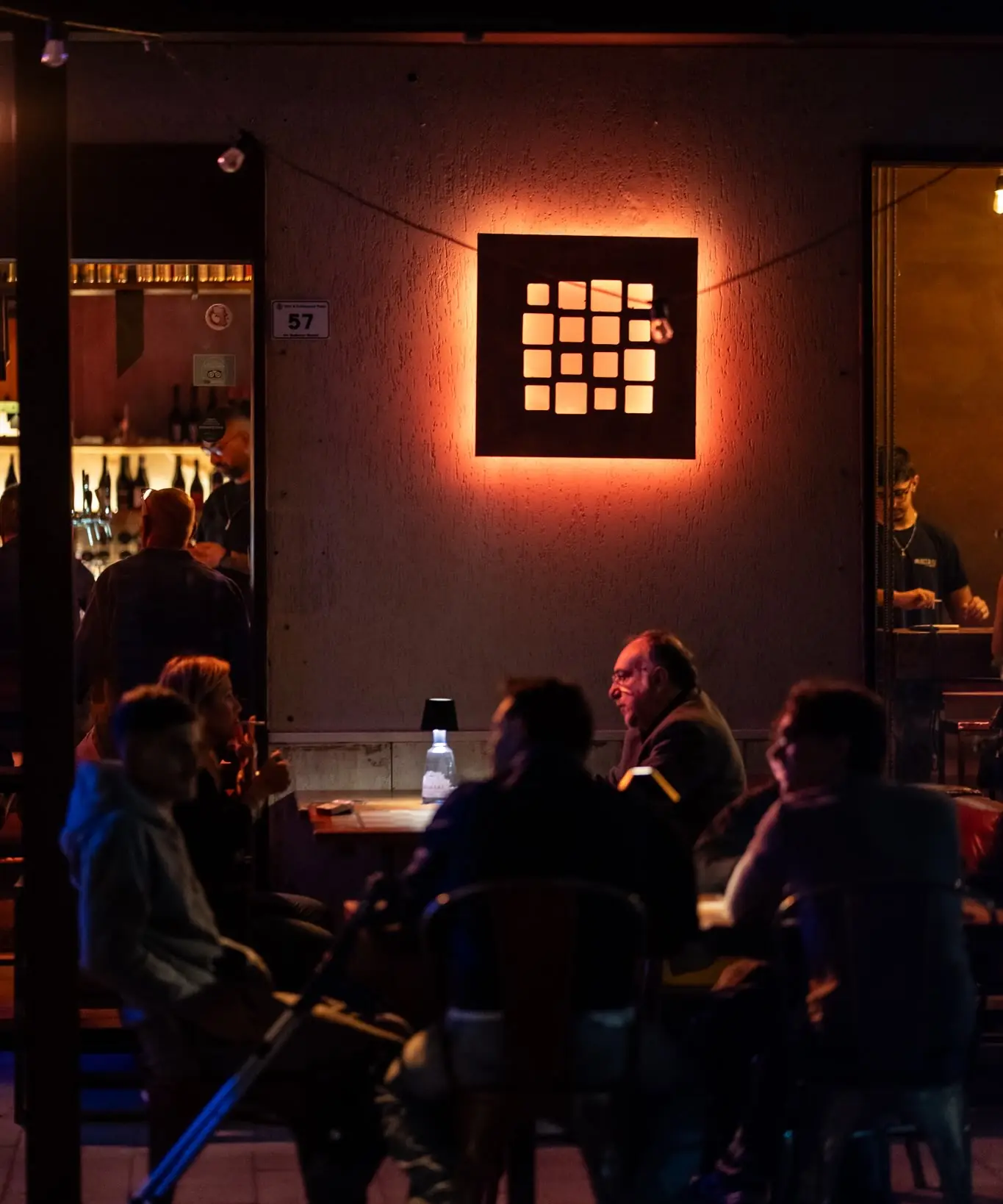 La sala di sera, con il logo luminoso a quadrati sulla parete e i tavoli occupati
