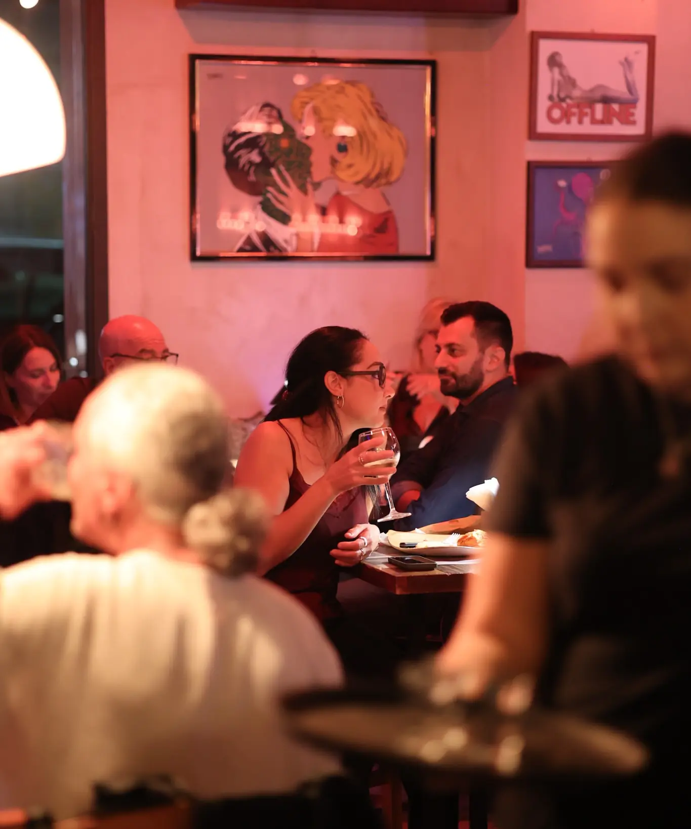 Una tavolata di amici a cena nella sala illuminata di rosa